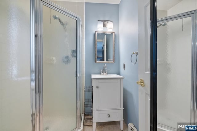 bathroom featuring vanity, a shower stall, and a baseboard radiator