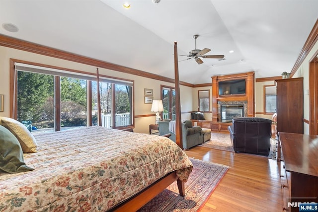 bedroom with a glass covered fireplace, lofted ceiling, light wood finished floors, and ornamental molding