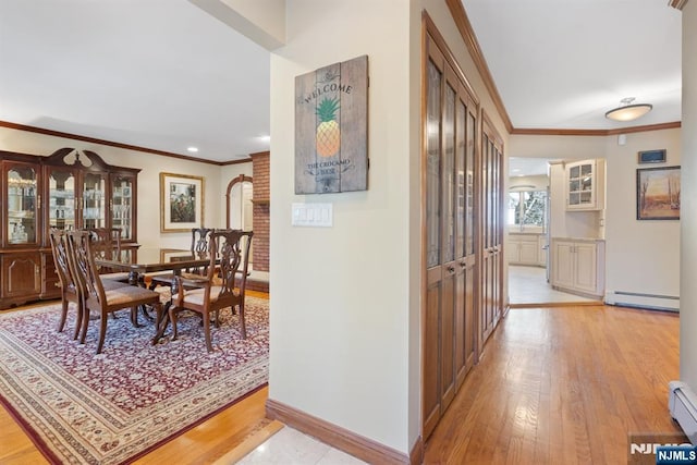 hall featuring light wood-style floors, a baseboard radiator, and ornamental molding