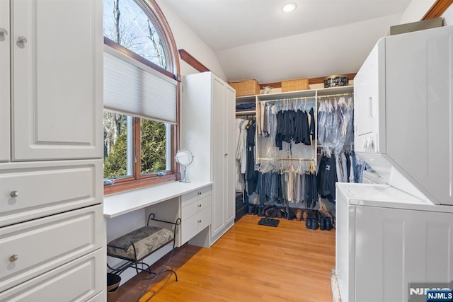 spacious closet with stacked washing maching and dryer and light wood-style floors