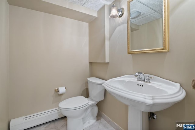 half bathroom with baseboards, baseboard heating, and toilet