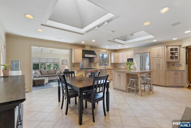 dining space with a tray ceiling, a skylight, plenty of natural light, and crown molding