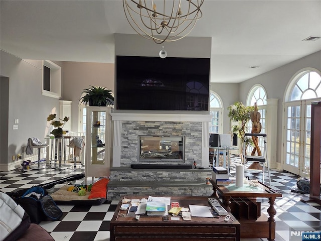 living area featuring tile patterned floors, a stone fireplace, a notable chandelier, and visible vents