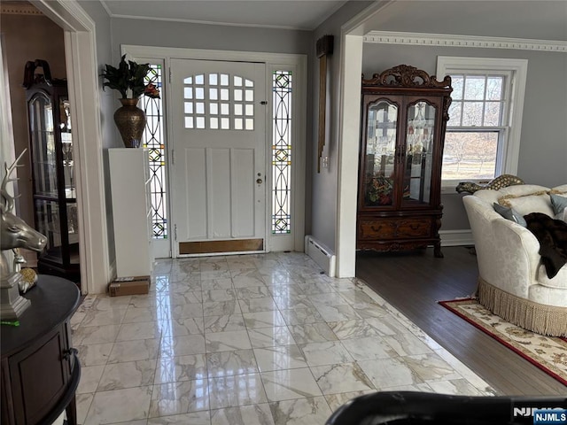 entryway with a baseboard heating unit, crown molding, and marble finish floor