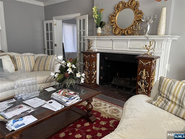 living room with a tiled fireplace, wood finished floors, and ornamental molding