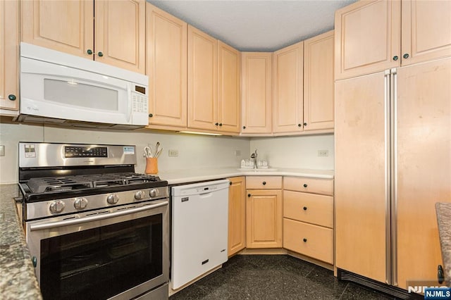 kitchen with light brown cabinetry, white appliances, granite finish floor, and light countertops