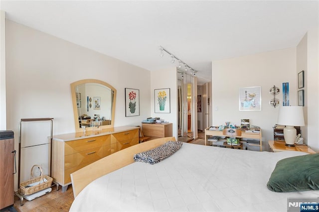 bedroom featuring wood finished floors and rail lighting