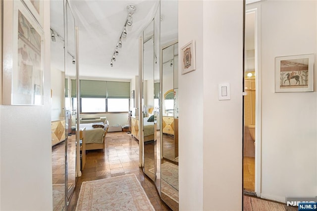 corridor with stone tile floors and track lighting