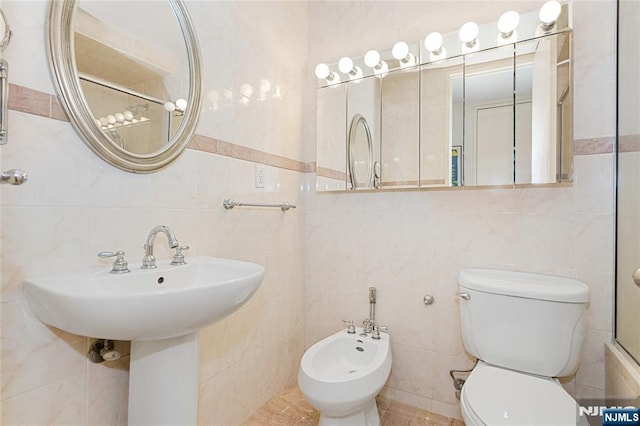 bathroom with a shower, tile walls, toilet, a bidet, and a sink