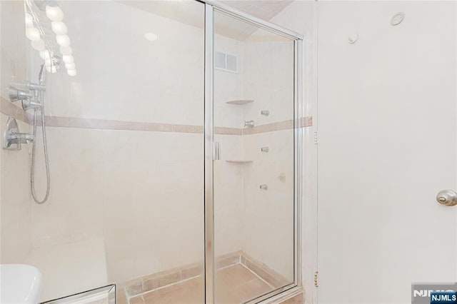 bathroom featuring toilet, a stall shower, and visible vents