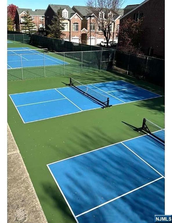 view of tennis court with fence and a residential view