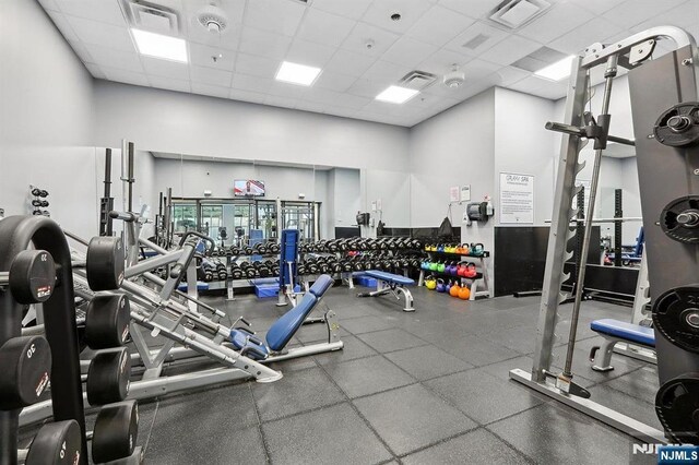 workout area with a paneled ceiling, visible vents, and a towering ceiling