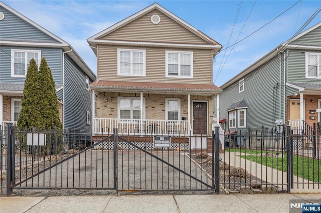 view of front of property with a porch, a gate, brick siding, and a fenced front yard