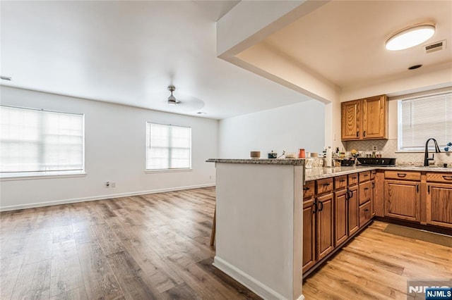 kitchen with tasteful backsplash, light wood-style flooring, a sink, and visible vents