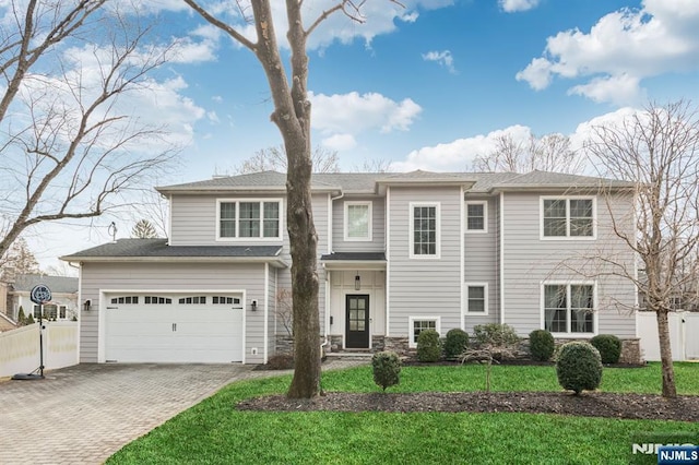 view of front of home featuring stone siding, a front lawn, decorative driveway, and fence