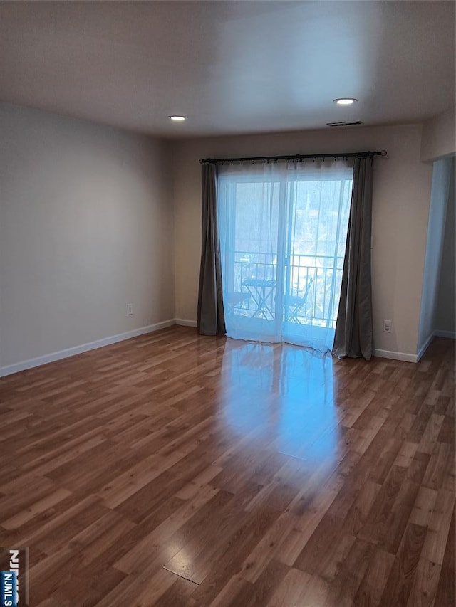 empty room featuring visible vents, baseboards, wood finished floors, and recessed lighting