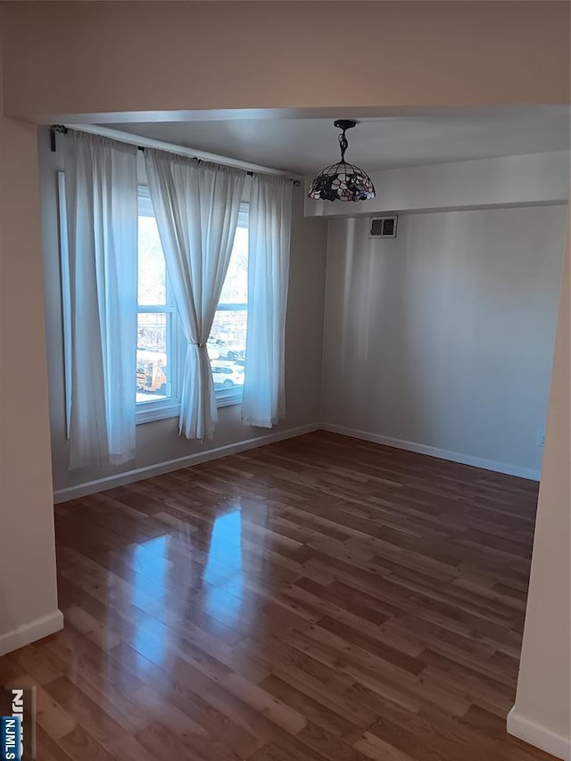 unfurnished room with wood finished floors, visible vents, and baseboards