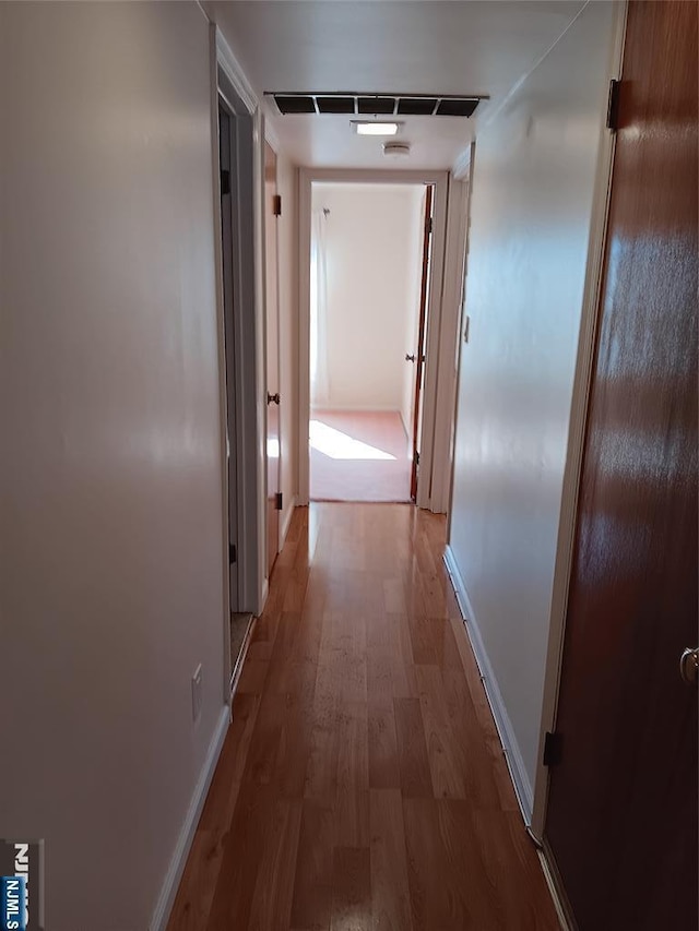 hallway featuring baseboards and wood finished floors