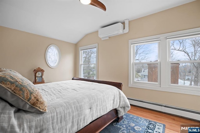 bedroom with lofted ceiling, baseboard heating, ceiling fan, wood finished floors, and a wall mounted air conditioner