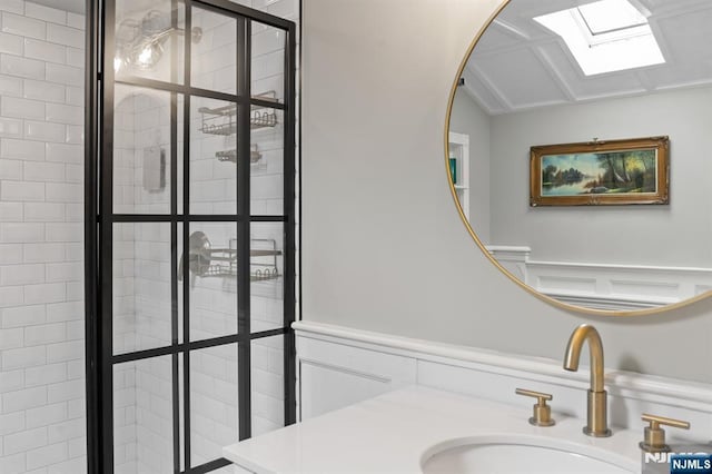 full bathroom with a stall shower, vaulted ceiling with skylight, and vanity