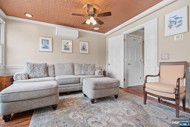 living area featuring ceiling fan, wood finished floors, ornamental molding, a wall mounted AC, and wainscoting