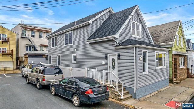 view of front of property with a shingled roof and fence