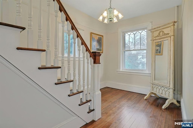 interior space featuring wood-type flooring, baseboards, and a notable chandelier