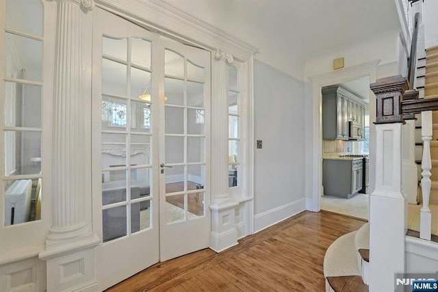 entryway with french doors, decorative columns, stairway, light wood-style floors, and baseboards