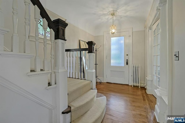 entrance foyer featuring radiator heating unit, stairway, and wood finished floors