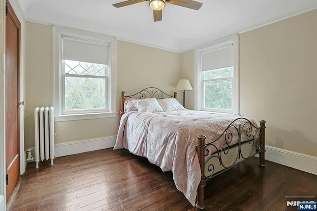 bedroom featuring dark wood-style floors, radiator, crown molding, and baseboards