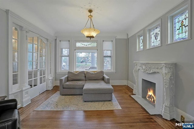 sunroom / solarium featuring a high end fireplace, plenty of natural light, and ornate columns