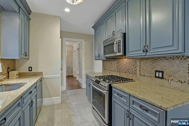 kitchen with light stone counters, stone tile floors, stainless steel appliances, decorative backsplash, and baseboards