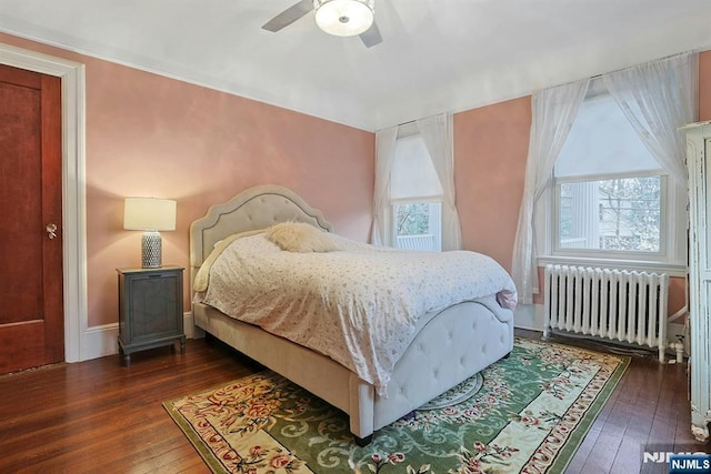 bedroom with a ceiling fan, baseboards, hardwood / wood-style floors, and radiator heating unit