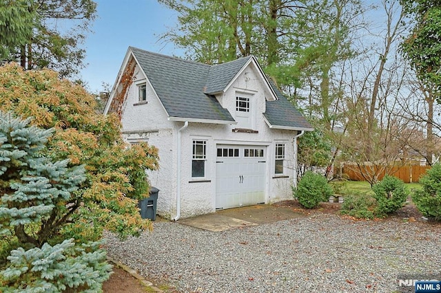 garage featuring gravel driveway and fence