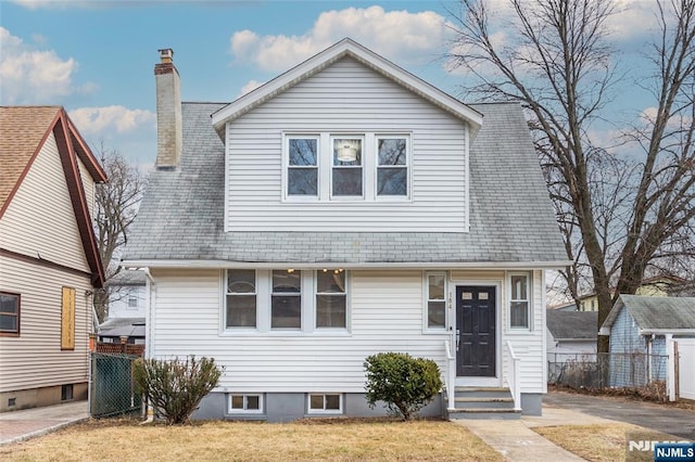 view of front of home featuring entry steps, a chimney, a front yard, and fence