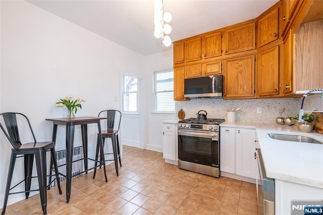 kitchen with stainless steel appliances, light countertops, a sink, and tasteful backsplash