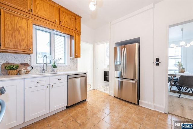 kitchen with brown cabinetry, decorative backsplash, stainless steel appliances, light countertops, and a sink