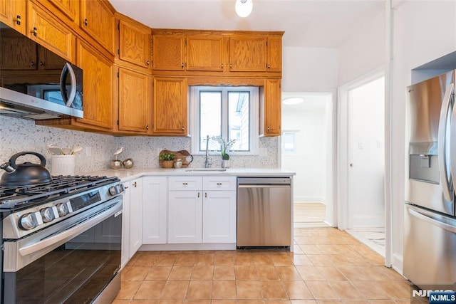 kitchen with light tile patterned floors, stainless steel appliances, light countertops, decorative backsplash, and a sink