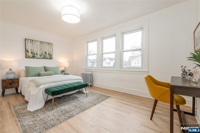 bedroom with light wood-style floors, baseboards, and radiator heating unit