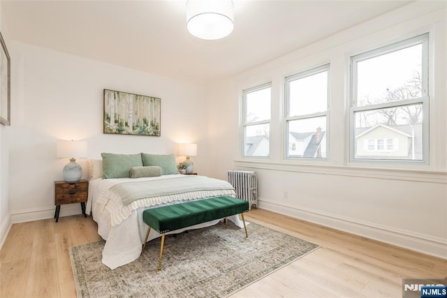 bedroom featuring light wood-style floors, baseboards, and radiator heating unit