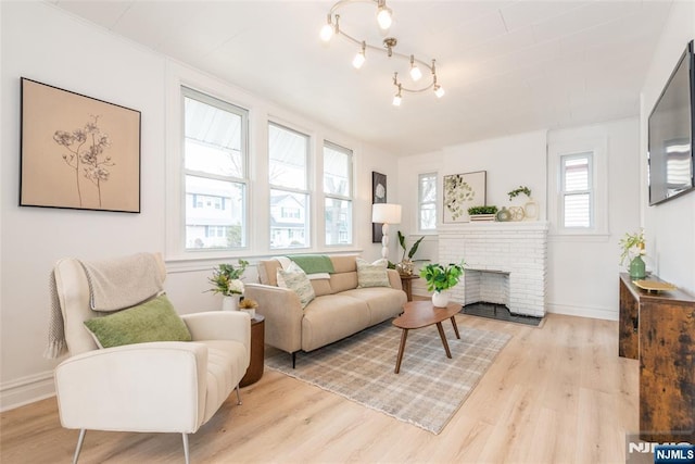 living area featuring a brick fireplace, baseboards, and wood finished floors