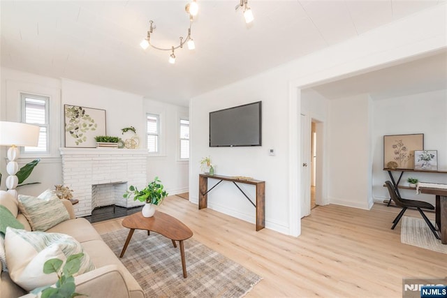 living area featuring light wood-style flooring, a fireplace, baseboards, and a wealth of natural light