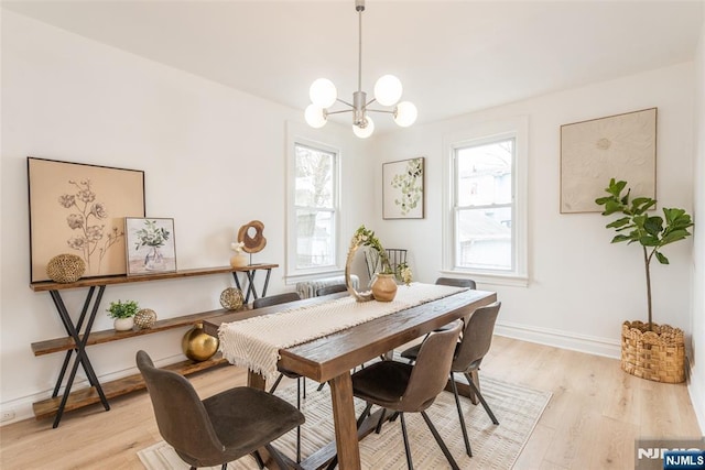 dining space with light wood-style floors, a notable chandelier, and baseboards