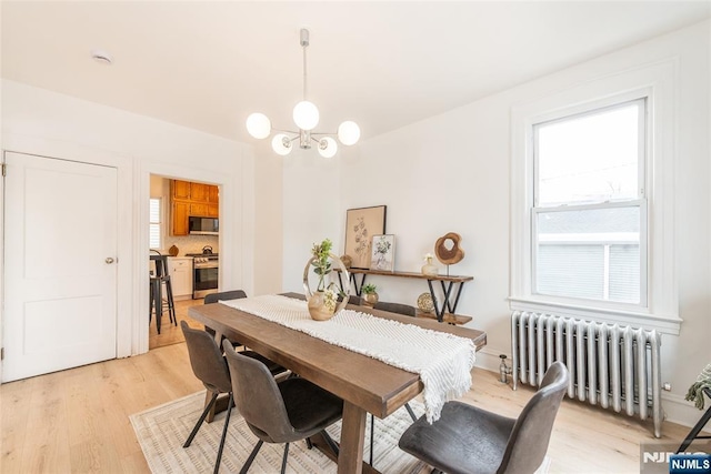 dining space with light wood-style floors, radiator heating unit, and an inviting chandelier