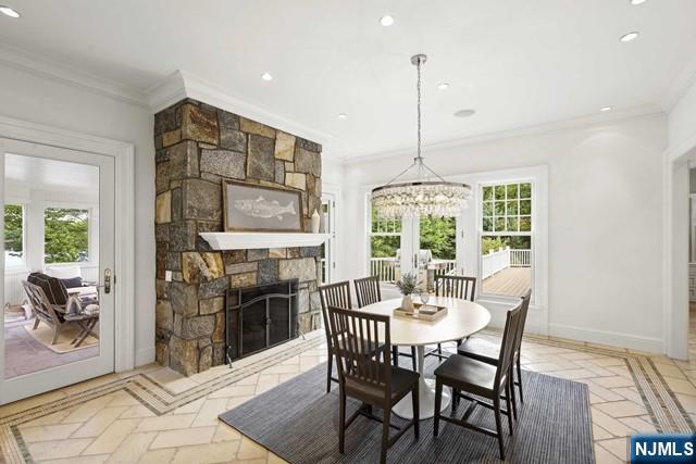 dining area featuring baseboards, ornamental molding, a stone fireplace, and recessed lighting