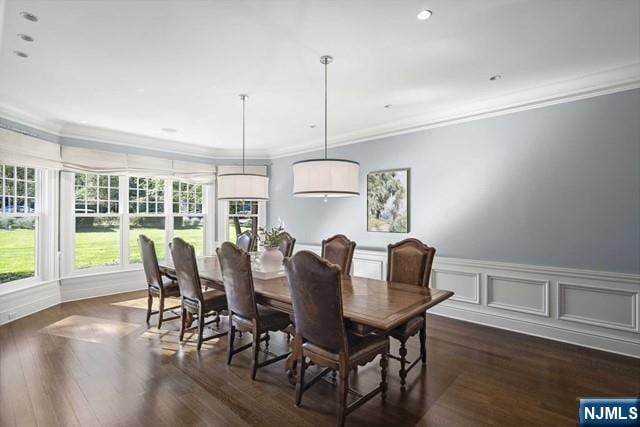 dining room featuring a wainscoted wall, a decorative wall, dark wood-style flooring, and crown molding