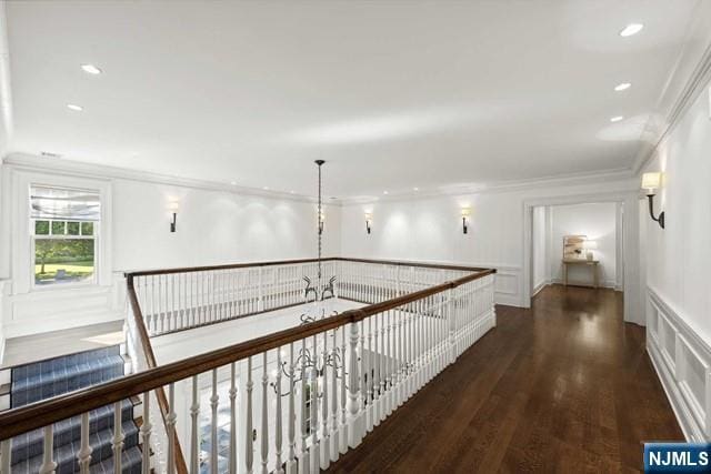 hallway featuring crown molding, recessed lighting, a decorative wall, wainscoting, and wood finished floors