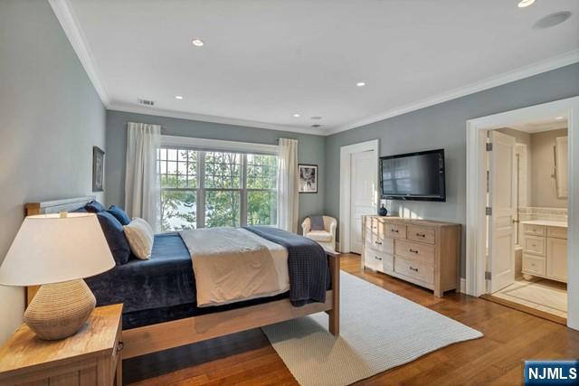 bedroom featuring recessed lighting, crown molding, ensuite bathroom, and wood finished floors