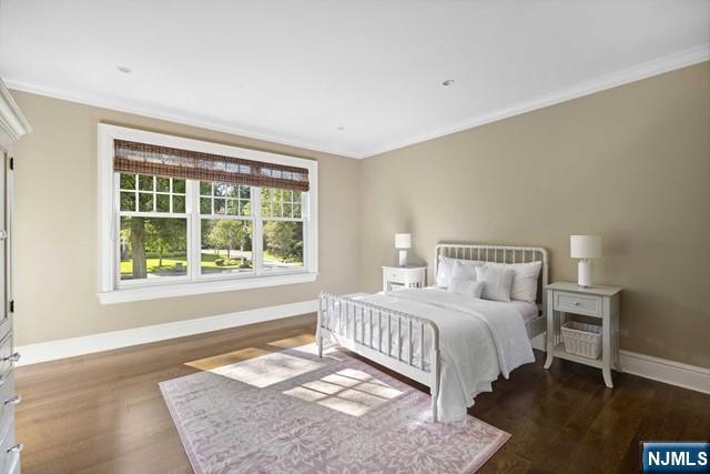 bedroom with baseboards, wood finished floors, and ornamental molding