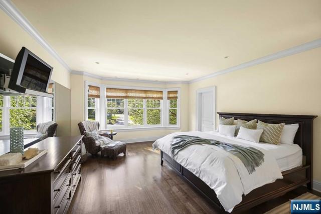 bedroom featuring ornamental molding, multiple windows, baseboards, and wood finished floors